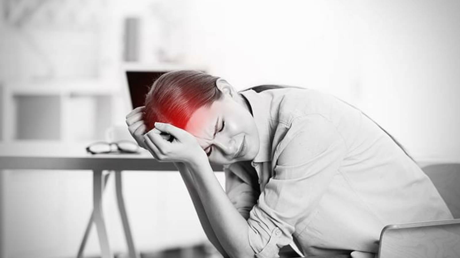 Young woman suffering from headache while working in office